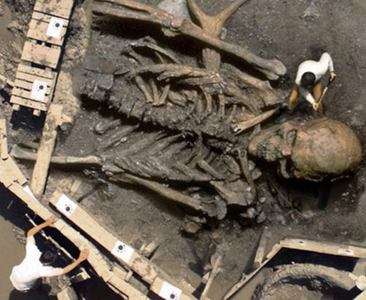 Giants by IronKite: a digitally composited human skeleton beside small excavation workers and a wooden platform.