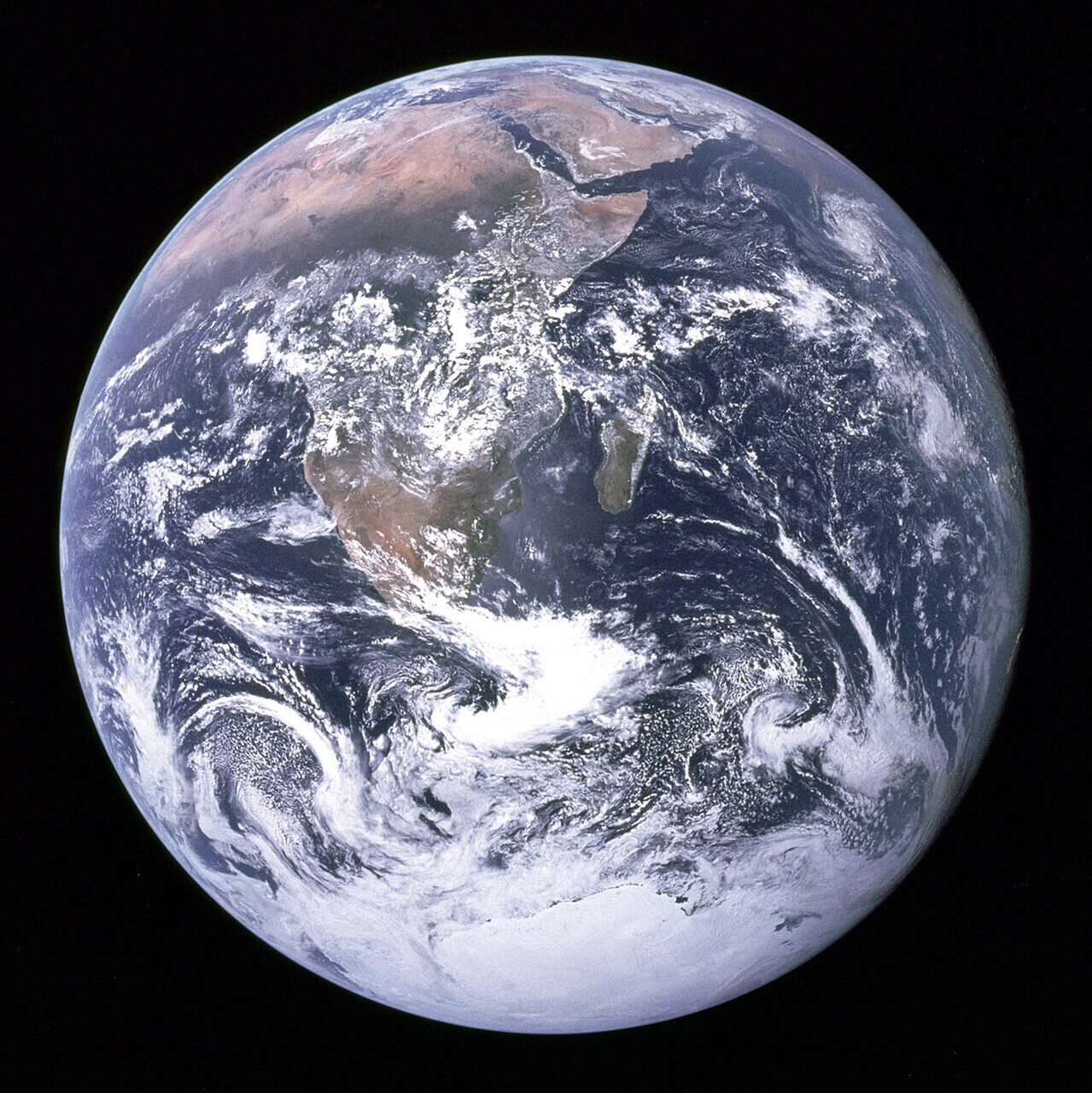 The Earth as a full, sunlit disc against black space, with Africa and swirling white cloud visible.